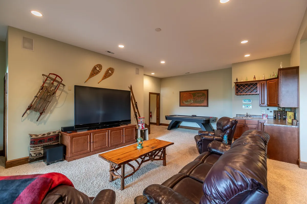 A spacious, comfortable game room featuring a large television, a pool table, wooden coffee table, and recreational decor. The setting is inviting, with ample space for unwinding or socializing after a productive work session.