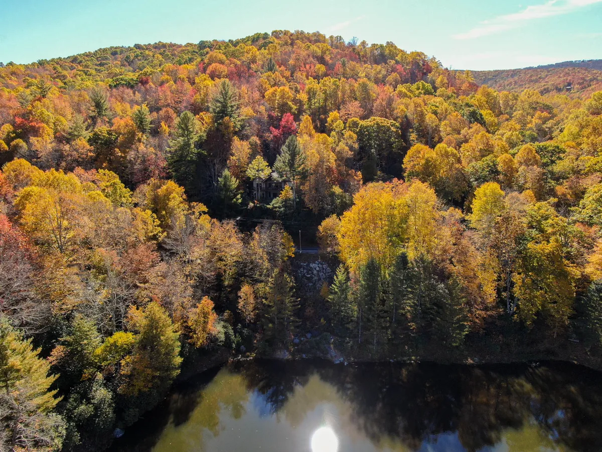 A tranquil lakeside view with reflective water bordered by vibrant autumn trees and a distant hillside. The scene is perfect for boating, hiking, and nature walks, capturing the picturesque environment surrounding Buckeye Lake.