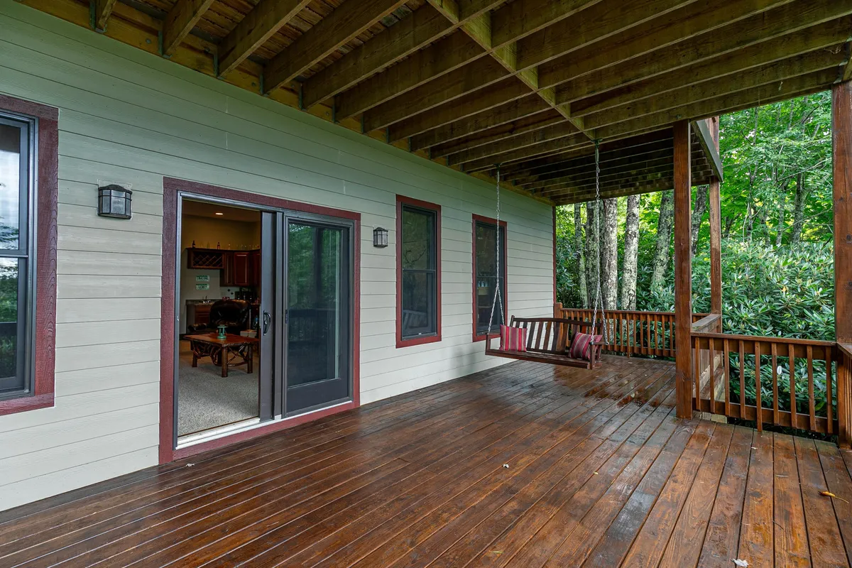 A relaxing swing hangs on a lower deck, framed by wooden railings and leafy surroundings. The setup feels intimate and peaceful, ideal for reading a book, quiet conversations, or simply enjoying the sights and sounds of nature.